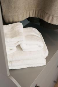 a stack of white towels sitting on a shelf at Superb 4BR New House in Leeds