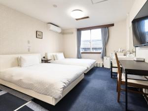 una camera d'albergo con due letti e una scrivania di Okasan Hotel a Ogaki