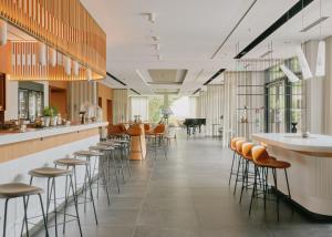 ein Restaurant mit Hockern und eine Bar mit Klavier in der Unterkunft Lufthansa Seeheim - More than a Conference Hotel in Seeheim-Jugenheim