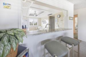 a kitchen with a counter with two chairs and a sink at Loggerhead 424 condo in Sanibel