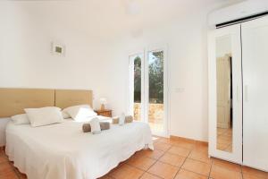 a white bedroom with a bed and a window at Villa AMOROS in Alcudia +27 photos
