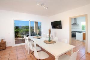 a white dining room with a white table and chairs at Villa AMOROS in Alcudia