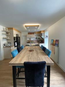 a large wooden table in a kitchen with blue chairs at Lady Jule Chambres d hôtes & spa in Sainte-Luce-sur-Loire