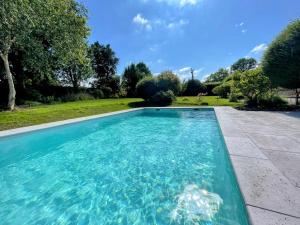 a swimming pool with blue water in a yard at La Chaumière Normande in Vattetot-sous-Beaumont