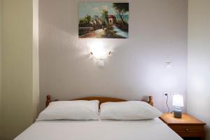 a bed with two pillows and a painting on the wall at Lucia Hotel Paralia in Paralia Katerinis +67 photos