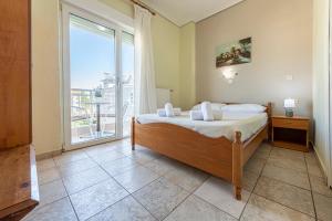 a bedroom with a bed and a large window at Lucia Hotel Paralia in Paralia Katerinis