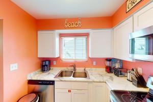 a kitchen with a sink and an orange wall at Summer House West Condos in Gulf Shores +86 photos