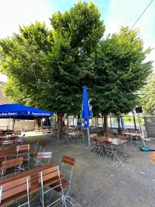 a group of tables and chairs with a tree and blue umbrellas at Gasthaus - Hotel Neue Post in Meitingen