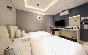 a bedroom with two beds and a desk with a television at Heimish Hotel in Tongyeong