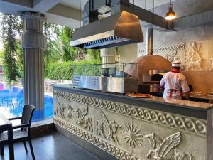 un uomo in piedi in una cucina con forno per pizza di Delux Apartment Argisht Golden Sands a Golden Sands