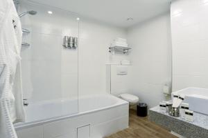 a white bathroom with a tub and a toilet at Rise Urban Art Hotel in Larnaca