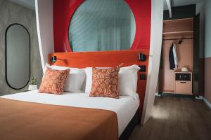 a bedroom with a bed with a red headboard and two mirrors at DuoMo Hotel in Rimini
