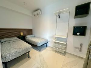 San ĠwannにあるPauliz Apartmentsのベッド2台とテレビが備わる小さな客室です。