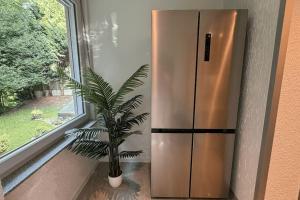 a plant sitting next to a stainless steel refrigerator at Geräumiges Apartment mit XXL Leinwand I Parkplatz I WiFi in Bochum