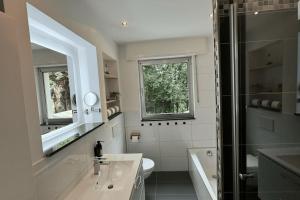 a bathroom with a sink and a toilet and a mirror at Geräumiges Apartment mit XXL Leinwand I Parkplatz I WiFi in Bochum +60 photos