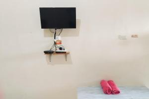 deux oreillers rouges posés sur un lit avec une télévision dans l'établissement RedDoorz Syariah at Shakira Alesha Enggal, à Bandar Lampung