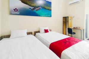 deux lits côte à côte dans une pièce dans l'établissement RedDoorz Syariah at Shakira Alesha Enggal, à Bandar Lampung