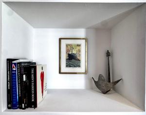 a shelf with books and a picture on a wall at La Teresiana apartment in Trieste