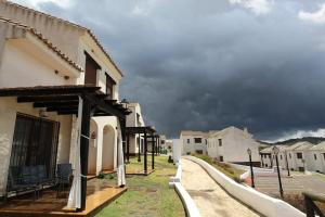 eine Gruppe von Gebäuden auf einer Straße mit wolkigem Himmel in der Unterkunft La casa de la encina in El Ronquillo