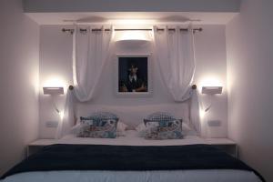 a bedroom with a white bed with two blue pillows at The White Knight Premium Boutique Hotel in Għajnsielem