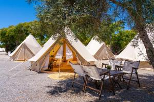 a group of tents with a table and chairs in front at Kampaoh Tavira in Tavira