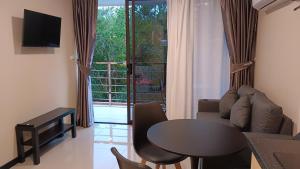 a living room with a table and a couch and a window at Rawai Beach Condo by Holy Cow in Nai Harn Beach