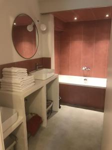 W łazience znajduje się umywalka, wanna i lustro. w obiekcie Maison Lavenir w mieście Annonay