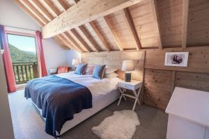 a bedroom with a bed and a large window at Chalet des Cousins: Fantastic alpine chalet in Vaujany