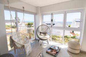 a living room with swinging chairs and a view of the ocean at Shelley Point Estate Blue Avion Luxury Holiday Home Solar Powered in St Helena Bay