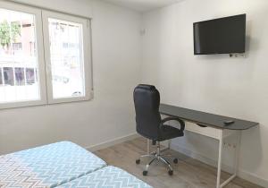 a bedroom with a desk and a chair and a television at Casa Pastor in Murcia