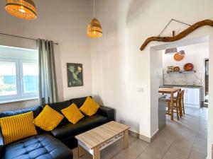 a living room with a black leather couch and yellow pillows at Casa de Aloe in Albufeira