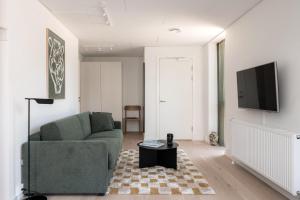 a living room with a green couch and a tv at Beach Gardens 46 by Daniel&Jacob's in Copenhagen