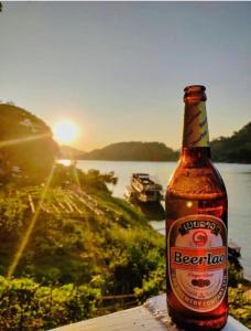 a bottle of beer sitting on a table next to a lake at Mekong Backpackers in Pakbeng