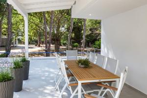 a wooden table and chairs on a patio with trees at Villa Karidi Vourvourou in Vourvourou