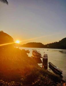 a group of boats docked on a river at sunset at Mekong Backpackers in Pakbeng