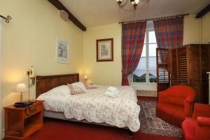 a bedroom with a bed and a red chair at Logis Cote Loire - Auberge Ligerienne in Blois