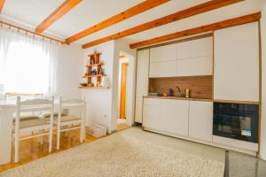 eine Küche mit weißen Schränken und einem Waschbecken und einem Tisch in der Unterkunft Villa Miris Prirode Zenik in Ilidža