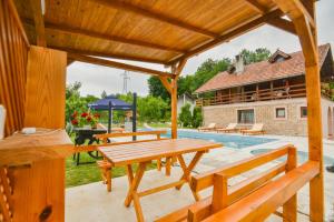 eine Terrasse mit einem Holztisch und Bänken neben einem Pool in der Unterkunft Villa Miris Prirode Zenik in Ilidža