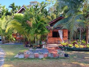 a house with palm trees in front of it at Alaska pool cafe&homestay2 in Ban Ton Pho