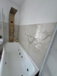 a white bath tub in a bathroom with a marble wall at Downtown luxury segment in Braşov +41 photos