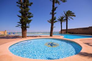 una piscina con palmeras y el océano en Apartamento Belvedere - Deniasol, en Denia