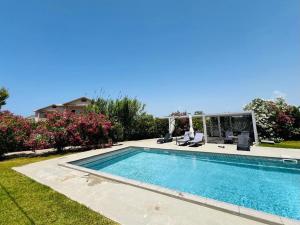 a swimming pool in a yard with two chairs at Lefkada Beach Villa in Lefkada