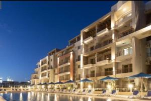 ein großes Gebäude mit Stühlen und Sonnenschirmen neben einem Pool in der Unterkunft 3 bedroom apartment Marina Residence New Alamein in El-Alamein