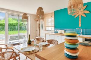 a kitchen with a table with a stack of plates at Maison pour 8 avec piscine 500m de la plage in Arradon