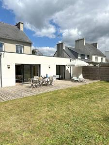 a house with a deck with a table and an umbrella at Grande Maison - Proche plages - Combrit Ste Marine in Combrit