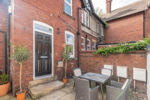 eine Terrasse mit einem Tisch und Stühlen vor einem Backsteingebäude in der Unterkunft Contractors Business Families Relocation Accommodation enjoy Fast WiFi Large Screen Smart TV and SKY Sports in this Spotless Ground Floor apartment in Wakefield