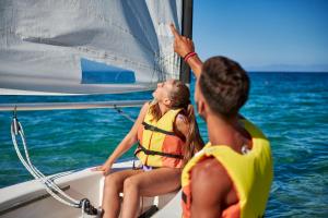 a man and woman in life jackets on a sail boat at Calaserena Resort in Geremèas