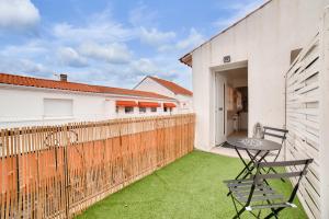 a patio with a table and a chair on the grass at 180m de la plage, quartier animé studio 2 personnes in La Tranche-sur-Mer