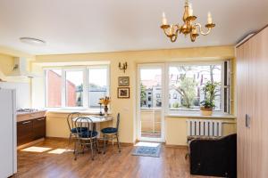 a kitchen with a table and chairs and windows at Golden Dune Apartment in Klaipėda