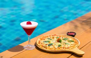 a pizza sitting on a table next to a drink at The Marina Phuket Hotel in Patong Beach